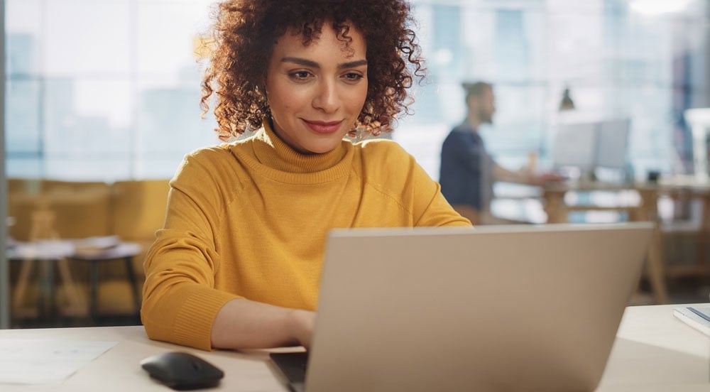 Sem Parar Empresas: mulher avaliando a política de benefícios da empresa em frente ao seu notebook