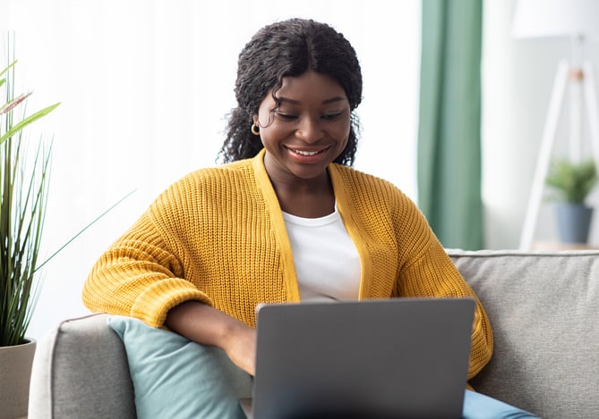 Mulher sorrindo com notebook no colo enquanto confere as categorias do cartão Multi da Sem Parar Empresas