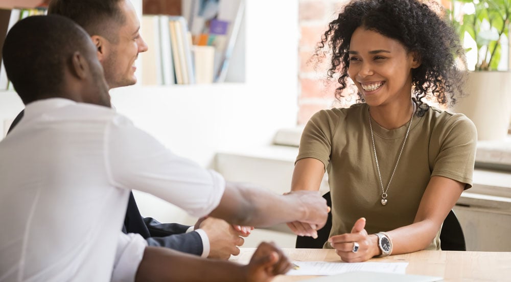 Sem Parar Emrpesas: três pessoas sorrindo em uma mesa, onde estão promovendo o reconhecimento de funcionários pelo seu esforço