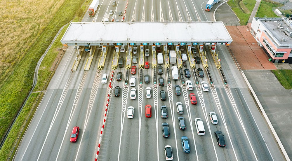 Praça de cobrança em rodovia vista de cima com inúmeros veículos que evitam a evasão de pedágio com a tag Sem Parar Empresas