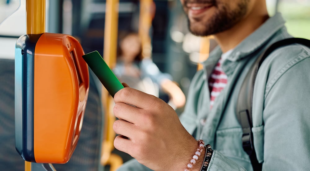 Um homem que é trabalhador temporário entrando em ônibus com seu vale-transporte da Sem Parar Empresas