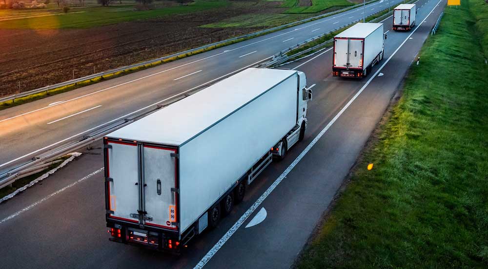 Três caminhões em fila em uma rodovia que foi mapeada pelo planejador de rotas do vale-pedágio Sem Parar Empresas