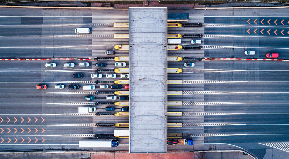 Sem Parar Empresas: praça de cobrança de rodovia com inúmeros veículos que devem calcular pedágio para o pagamento