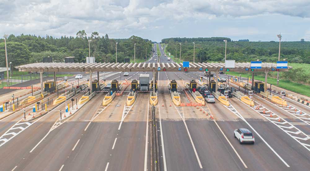 Praça de cobrança em rodovia com alguns carros e caminhões, onde deve ser usado o vale-pedágio obrigatório Sem Parar Empresas em casos de motoristas autônomos